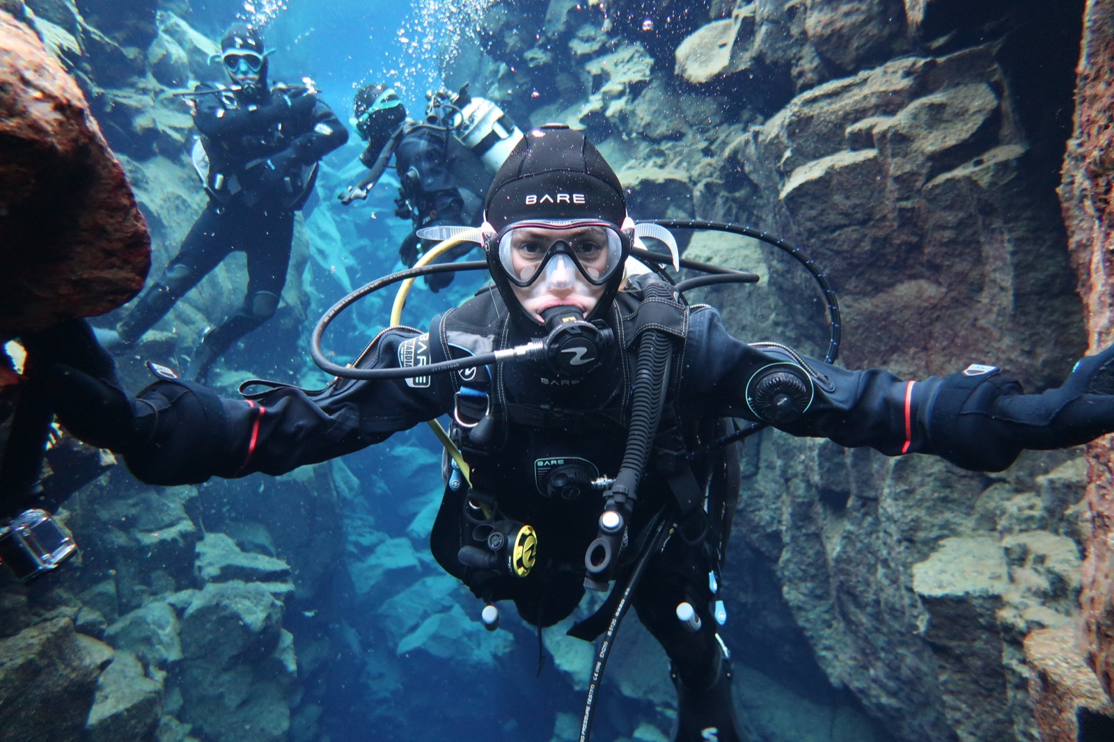 Diving through an underwater rock canyon with a group in Iceland